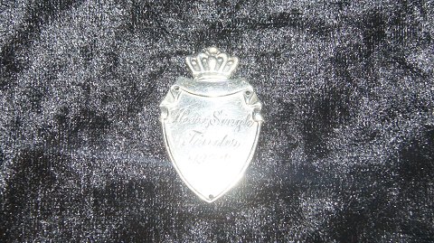 Emblem I Sølv med gravering på
Længde 4 cm
Brede 2,5 cm
Pæn stand