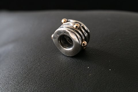 Charm til armbånd, fra  Pandora udført som cylender-formet med mønster med 
indlagt, små guld kugler. 925 sterling sølv.